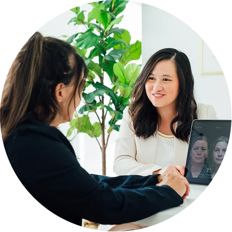 Doctor Tiffany Pham MD women shaking hands in modern office during video conference meeting with plant in background - in San Diego, CA.