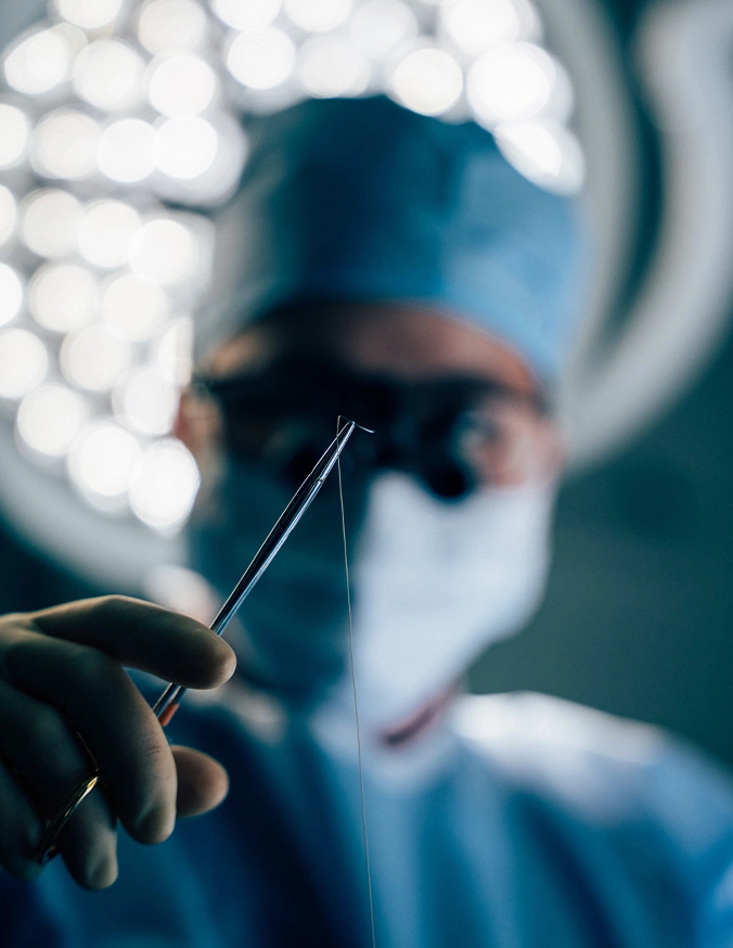 Doctor Tiffany Pham MD in blue scrubs and mask holding surgical scalpel during medical procedure in operating room - buccal fat pad removal in San Diego, CA