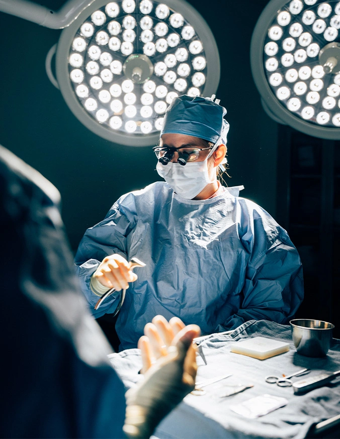 Doctor Tiffany Pham MD in blue scrubs and mask performing operation under surgical lights in operating room - Facial paralysis in San Diego, CA