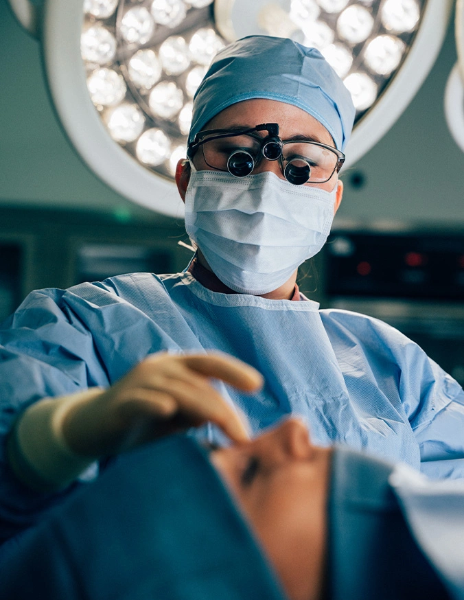 Doctor Tiffany Pham MD wearing surgical mask and magnifying loupes performing operation in modern operating room - Inferior Turbinate reduction in San Diego, CA