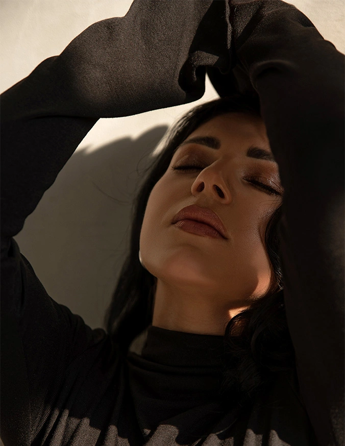 Person in black hoodie looking upward with hand near head in contemplative pose - Lip lift in San Diego, CA