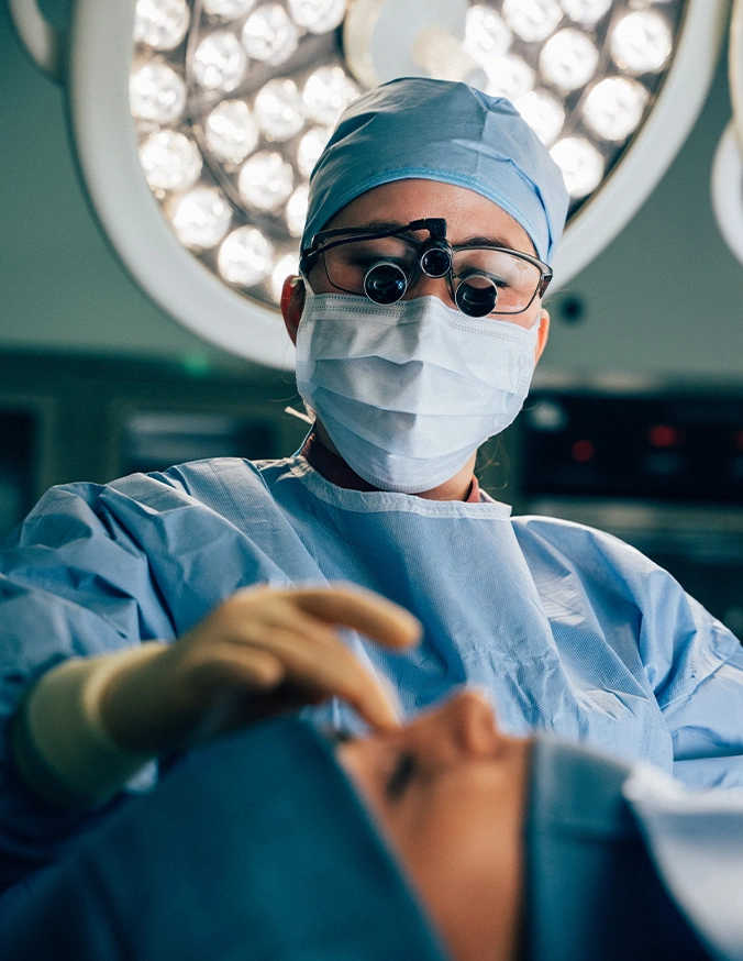 Doctor Tiffany Pham MD wearing surgical mask and magnifying loupes performing precision procedure in operating room - Nasal bone reduction in San Diego, CA