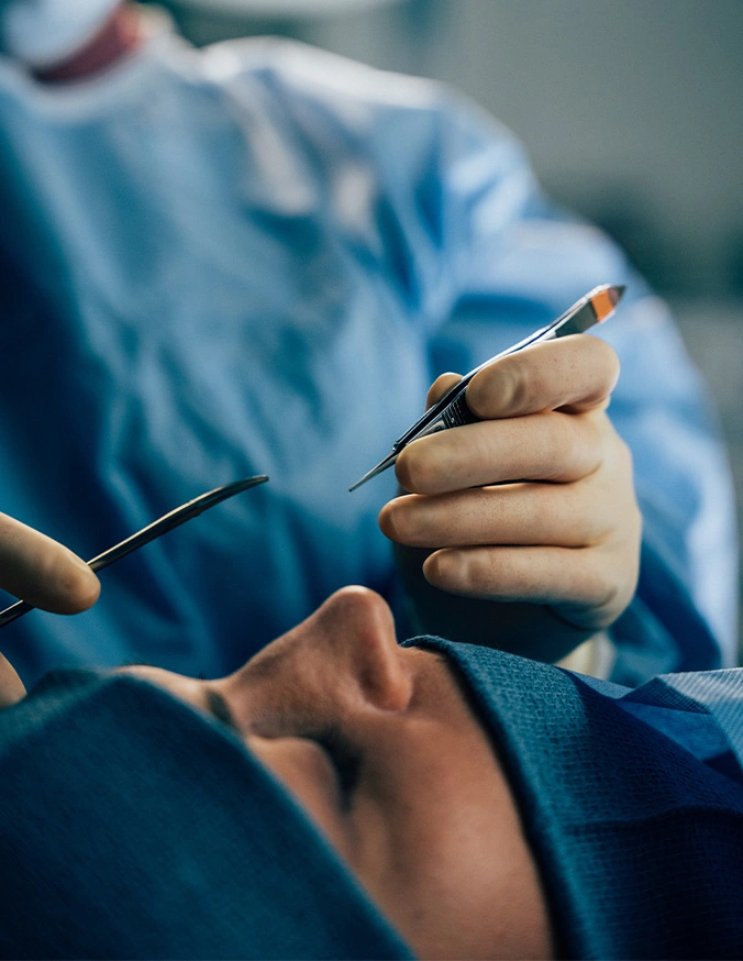 Surgeon's hands holding surgical instruments during medical procedure in operating room - Rhinoplasty in San Diego, CA