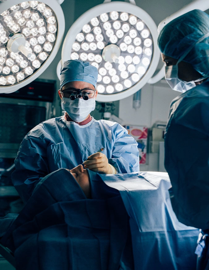 Doctor Tiffany Pham MD and nurse performing operation in operating room with surgical lights overhead - septoplasty in San Diego, CA